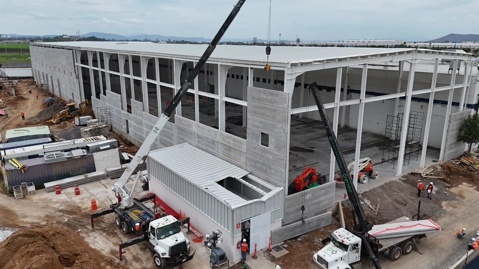 Dos camiones grúa Tensocret durante el montaje de paneles prefabricados de concreto en una nave industrial