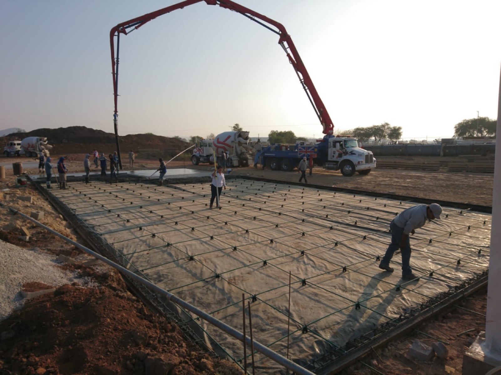 Colado de piso industrial postensado en obra con bomba de concreto sobre la malla de refuerzo
